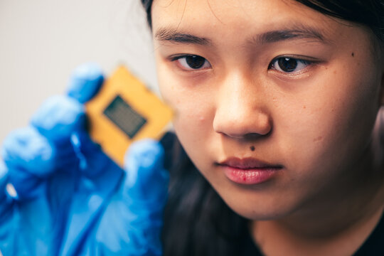 young female tech electronics engineer inspecting a CPU as a conceptual backdrop for artificial intelligence hardware technology innovation quality control