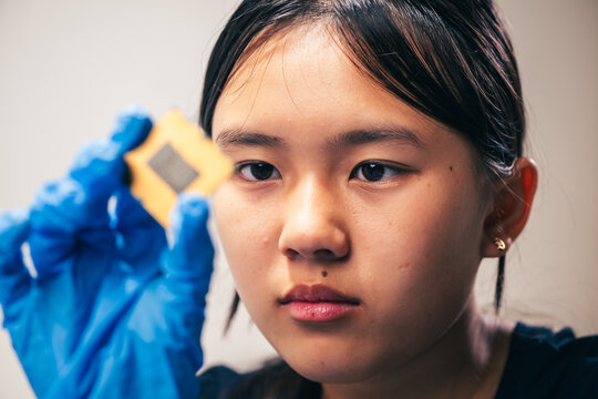 young female tech electronics engineer inspecting a CPU as a conceptual backdrop for artificial intelligence hardware technology innovation quality control