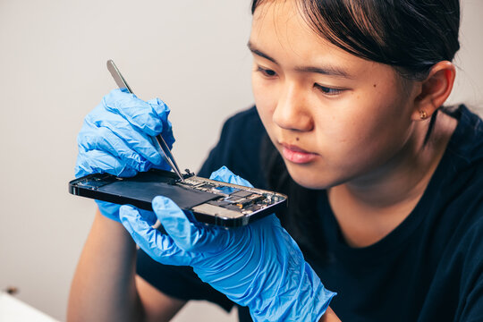 Female technician replaces smartphone lithium battery for hardware repair concept. Conceptual backdrop for phone repair service, right to repair microelectronics, and green circular economy 
