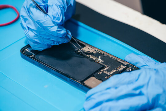 Female technician replaces smartphone lithium battery for hardware repair concept. Conceptual backdrop for phone repair service, right to repair microelectronics, and green circular economy 
