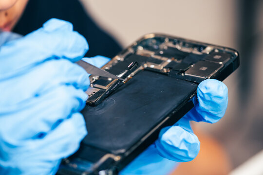 Female technician replaces smartphone lithium battery for hardware repair concept. Conceptual backdrop for phone repair service, right to repair microelectronics, and green circular economy 