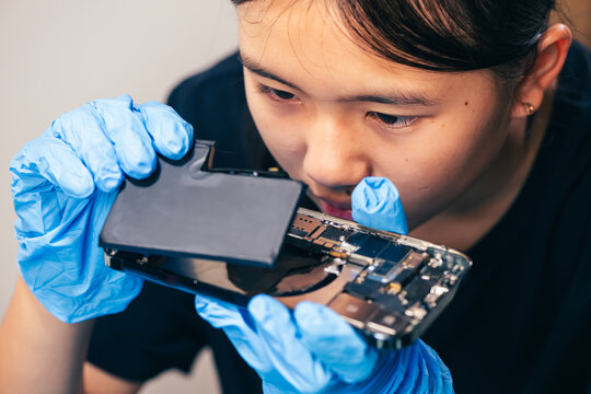 Female technician replaces smartphone lithium battery for hardware repair concept. Conceptual backdrop for phone repair service, right to repair microelectronics, and green circular economy 