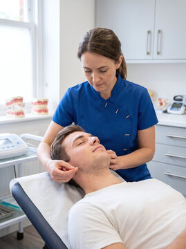 Female Physiotherapist Performing Dry Needling on Male Patient Jaw in Clinic