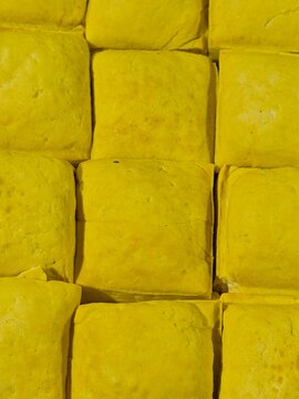 Yellow tofu blocks arranged, traditional Indonesian Tahu Bandung or Tahu Kuning made from soybeans and turmeric, top view full frame food background