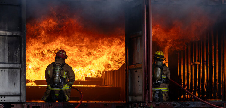 Team of firefighter in fireproof clothe with oxygen tank using twirl fog watering hose to put out the burning building with high flame for fire extinguish risk rescue mission and accident management