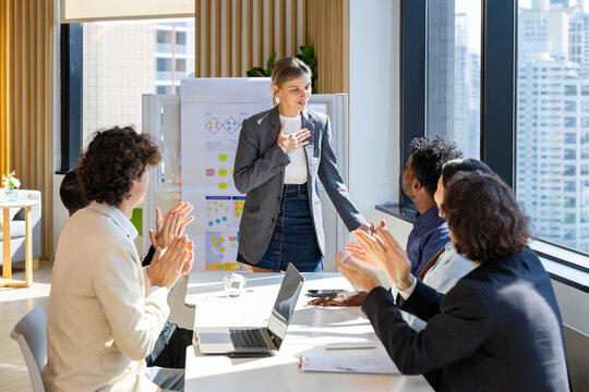 Newly promoted business manager is being humble with her team over new strategic strategy project on investment real estate with recognition and applause from other colleague for partnership