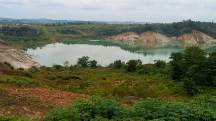Scenic panorama of turquoise lake in an abandoned mining site nestled within green mountain landscape © ketut