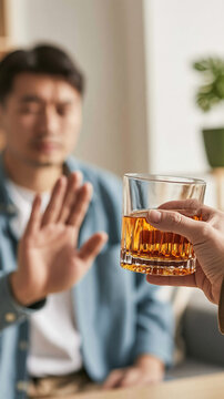 Refusal of Alcohol: A man makes a gesture of refusal, holding up his hand to decline a glass of amber liquid, symbolizing a choice for sobriety.