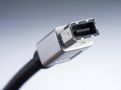 A firewire cable connector metallic and angular is displayed in a close up studio photograph ieee1394 electronics technology digital interface