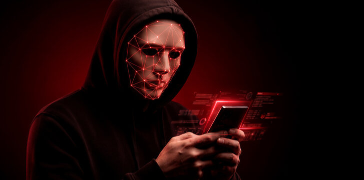 Hacker figure with glowing facial recognition mask using smartphone, digital data security and anonymity threat concept.
