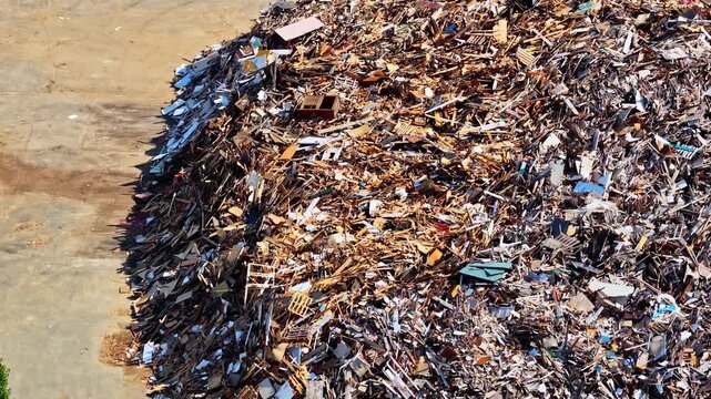 Aerial close up of massive pile of waste wood, broken pallets, furniture panels and demolition debris sorted for recycling at industrial yard in Port of Bordeaux, France