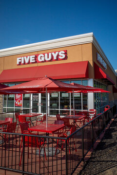 O&rsquo;Fallon, Illinois, USA &mdash; August 29, 2025: Five Guys restaurant storefront and empty outdoor dining patio with red tables, chairs, and branded umbrellas.