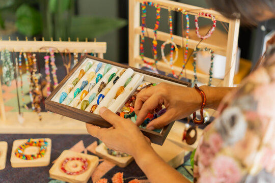 Asian Mature woman showing handcraft jewelry in hand for selling