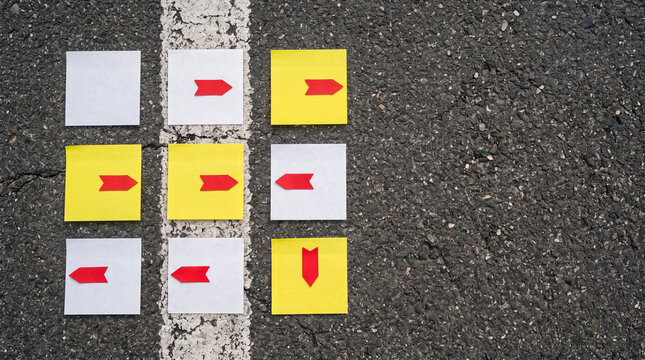 Top view of blank sticky notes with red arrow markers pointing different ways on asphalt beside faded lane line, crossroads decision concept 