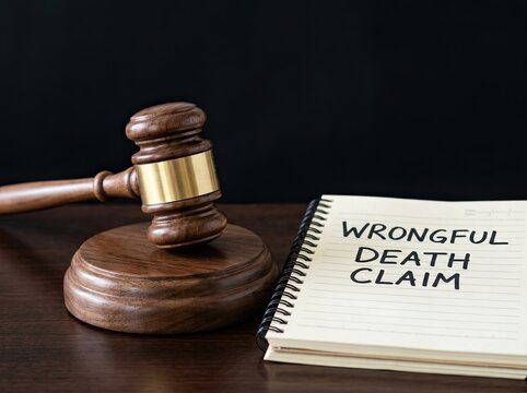 Wooden gavel next to wrongful death claim notebook ideal for legal services content representing legal liability justice and lawsuit rights