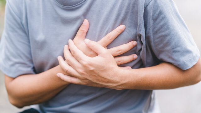 Unrecognizable male grabbing his chest experiencing acute left side chest pain. Depicting symptoms of myocardial infarction, severe heartburn, cardiac arrest, and critical health issues.