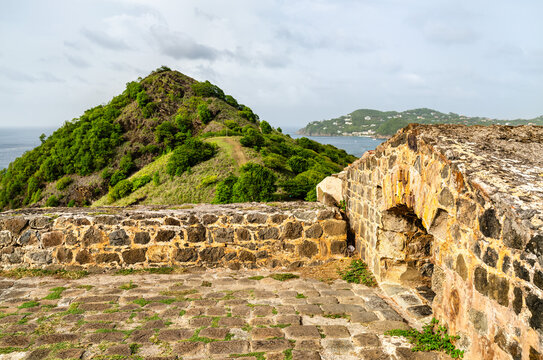 Historic stone fortification walls at Fort Rodney on Pigeon Island overlooking the green hills and Caribbean Sea in Saint Lucia.