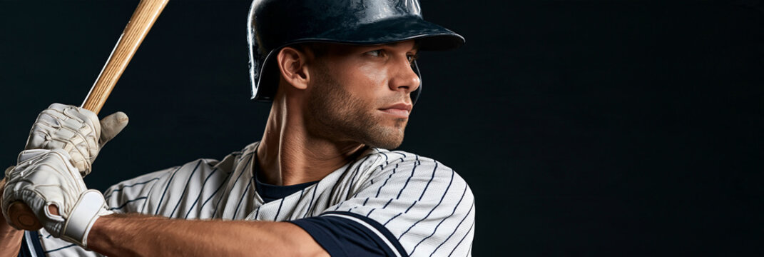 Baseball player grips bat, eyes focused ahead. Striped uniform, helmet, gloves signal readiness. Dark background contrasts with athlete's intense concentration. Perfect for sports, fitness