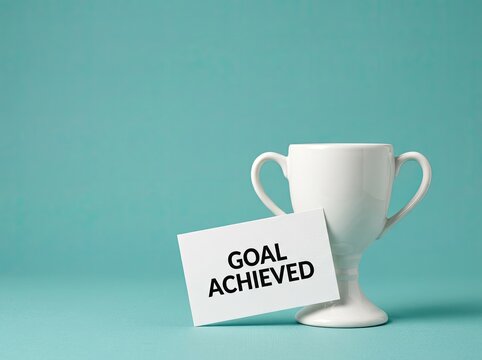 White trophy cup with goal achieved card on teal background ideal for business success media symbolizing victory effort and reaching targets