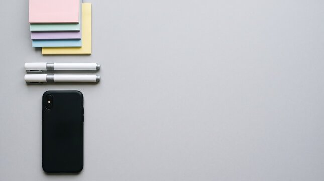 Minimalist flat lay featuring a black smartphone, pens, and sticky notes