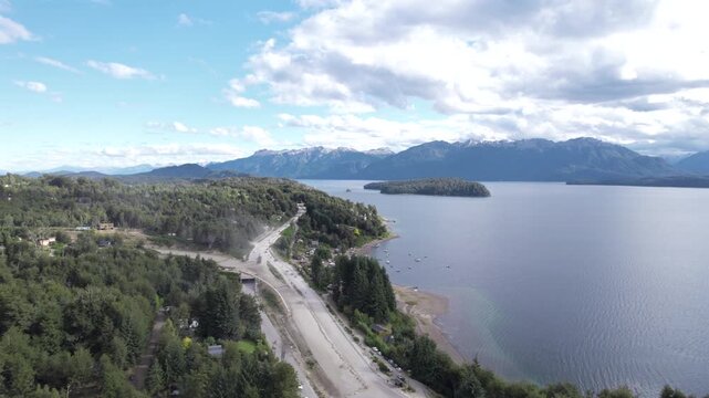 4K drone aerial view of Lake Nahuel Huapi in Patagonia, Argentina. Vast blue waters surrounded by lush forests and dramatic Andean mountains create a spectacular natural landscape.