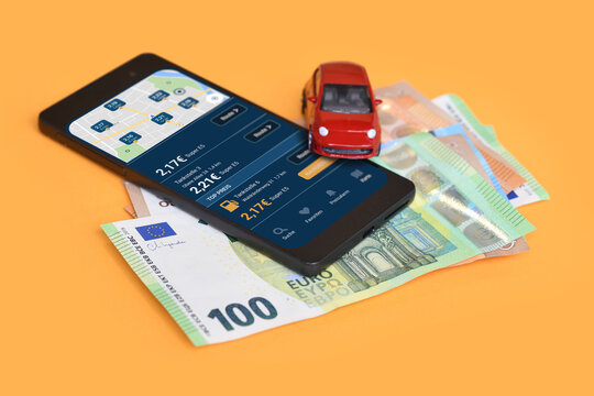 Smartphone displaying a German fuel discount app with high gasoline prices in Germany, money bills and car