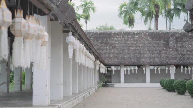 White temple colonnade hung with rows of Lanna paper lanterns
