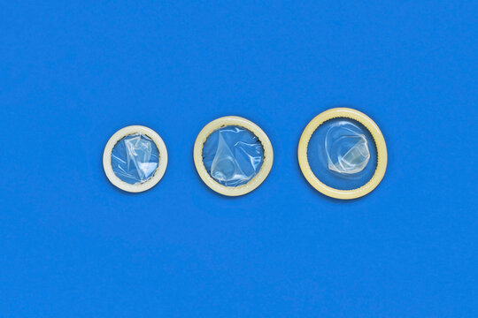 Three rolled condoms in a row showing large, medium and small sizes. Condom size comparison
