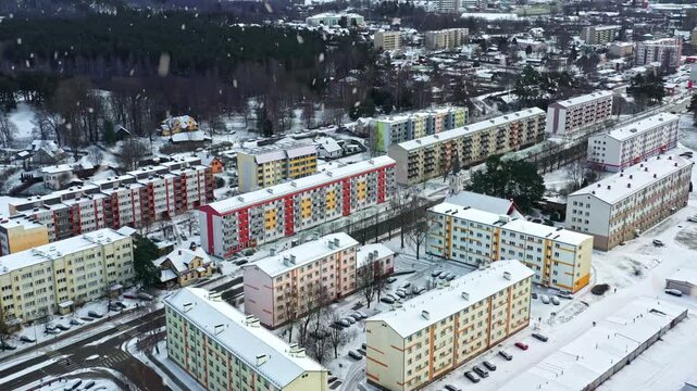 Urban area with soviet-era apartment blocks covered in snow during a gentle winter snowfall