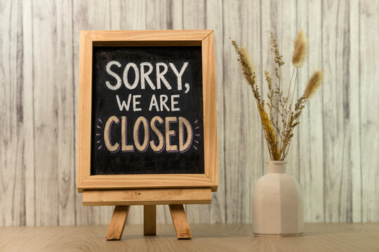 Sorry we are closed sign on a wooden chalkboard with dried flowers on a rustic table