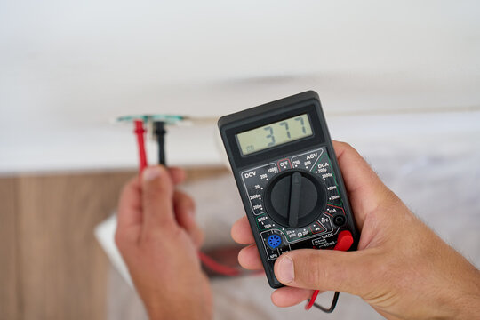 Electrician testing voltage with digital multimeter