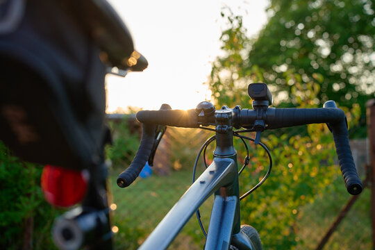 Gravel bike with handlebars and rear and front bicycle lights at sunset