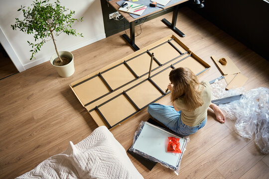 Woman assembling a metal shelving unit at home