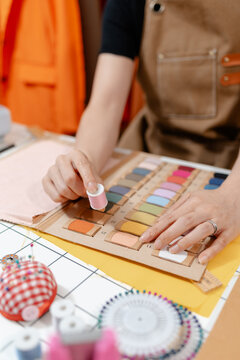 Professional fashion designer measuring fabric, selecting colors and preparing sewing equipment in a modern studio. Creative garment production, textile craftsmanship and apparel design.
