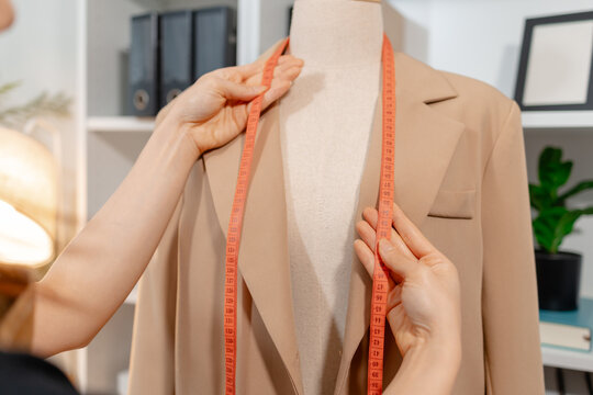 Fashion designer inspecting garment quality, measuring blazer fit and recording design details in a professional fashion studio. Apparel development, clothing quality control and textile craftsmanship