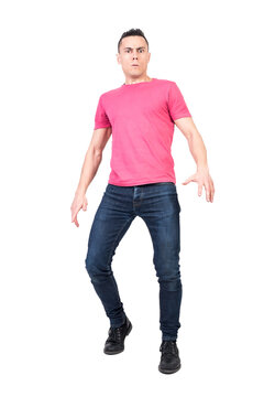 Full body of confused male looking at camera with concerned gaze while standing isolated in light studio