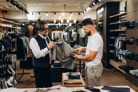 Salesperson helping customer choosing shirt in boutique