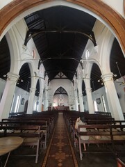 Interior of historic Christian church with wooden benches arches and stained glass window