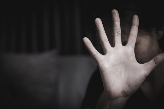 Woman showing stop hand gesture in dark room