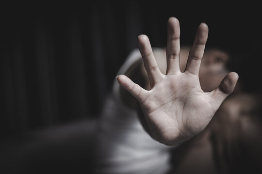 Woman with raised open hand in bedroom