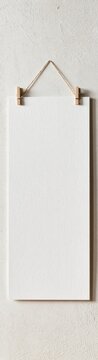 Blank white board hanging with rope and clips on textured wall