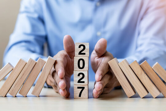 Businessman hand Stopping Falling of 2027 wooden Blocks. Business, Risk Management, Insurance, Resolution, strategy, solution, goal, New Year New You and happy holiday concepts