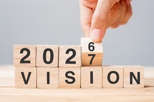 hand flipping block 2026 to 2027 VISION text on table. Resolution, strategy, goal, motivation, reboot, business and New Year holiday concepts