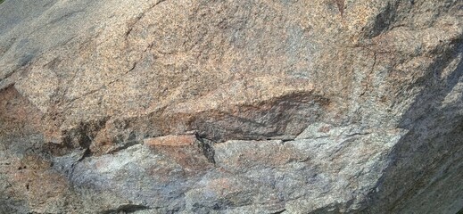 Close up detailed natural brown gray granite rock boulder texture background with rough rugged pattern and cracks © Douren
