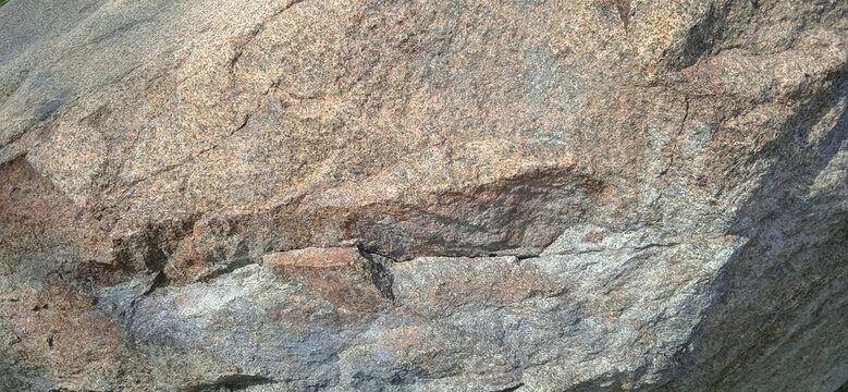 Close up detailed natural brown gray granite rock boulder texture background with rough rugged pattern and cracks