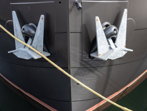 Twin Galvanized Anchors on Black Ship Bow with Crossed Mooring Ropes at Harbor Dock