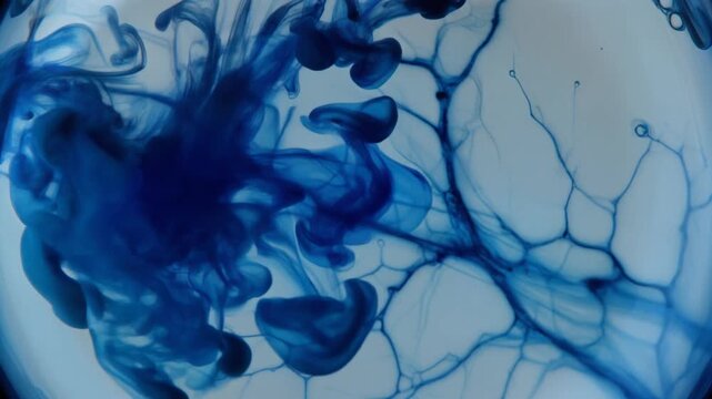 Abstract blue ink blooming in water creating delicate organic shapes and patterns like veins