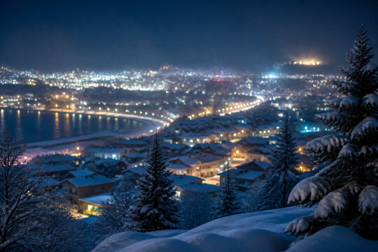 Snow covered town lights glowing at night seen from a hill