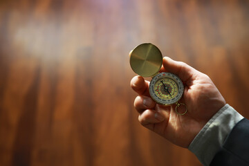 man in suit holding golden compass on gray background © alexkich