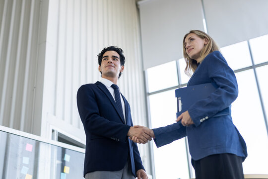 Confident business partner giving handshake after success corporate meeting in modern bright office showing professional trust and teamwork